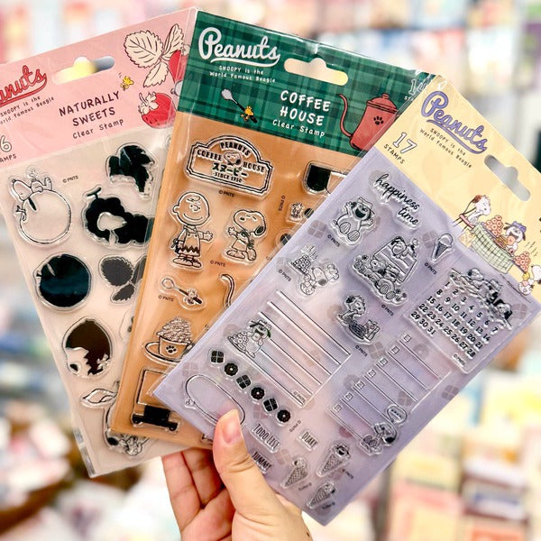 Snoopy coffee stamps pressed onto paper cards beside a handwritten coffee menu