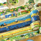 Rolls of BGM The Cat's Journey foil washi tape fanned out, showing the illustrated scenes