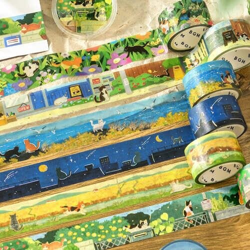 Rolls of BGM The Cat's Journey foil washi tape fanned out, showing the illustrated scenes