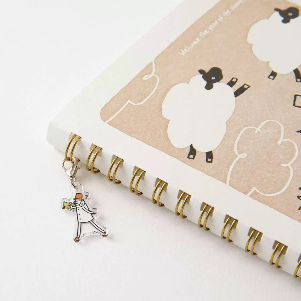 Open Ojisan notebook spread with the acrylic charm resting on the rings