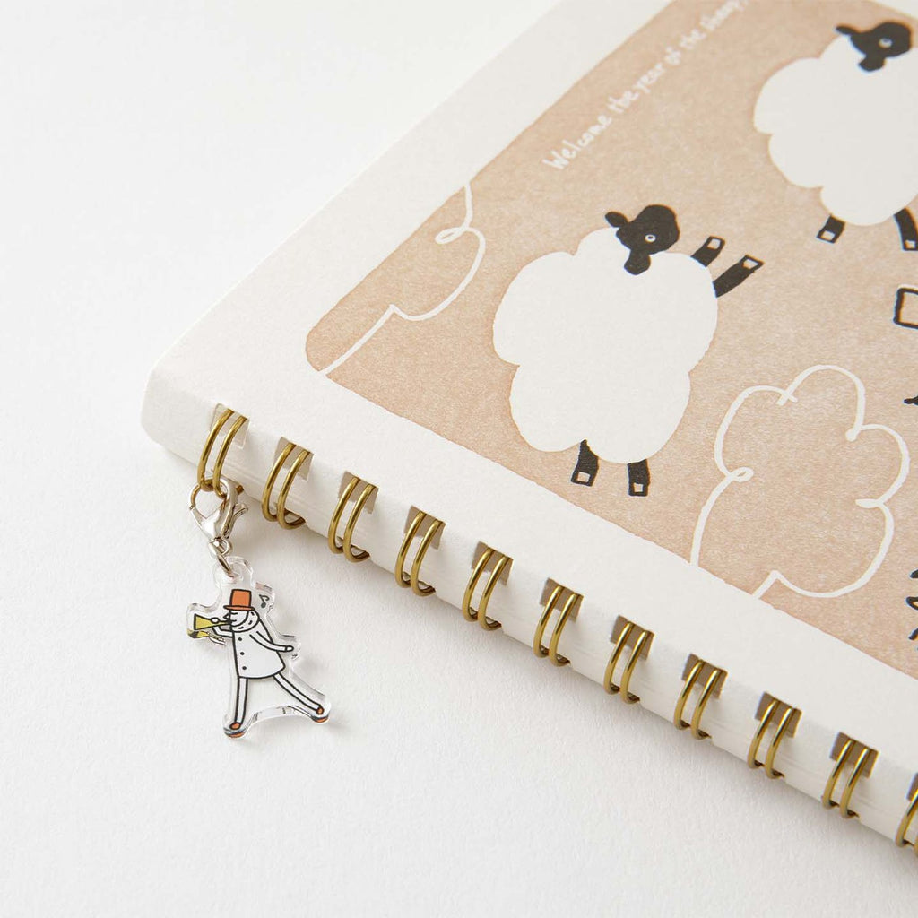Acrylic Ojisan charm attached to the notebook rings on a desk